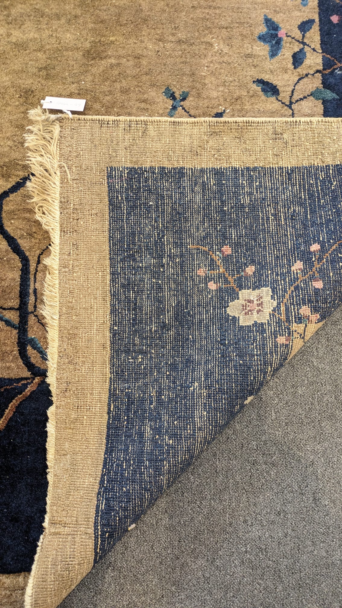 A Walter Nichols Chinese champagne ground carpet with asymmetrical decoration of flowers and an urn, single dark blue border, 350 x 280cm. Condition - fair